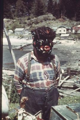 Man in mask, near village and shoreline