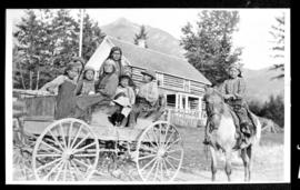 Group portrait of women and children on a wagon and boy on a horse