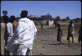 Man with shemma cloth next to a wall and a group of children