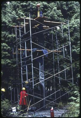 Workers prepare to move a totem pole