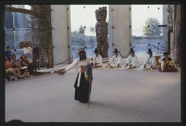 Masked Korean dancer holding a fan in front of performers with instruments