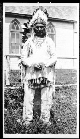 Portrait of a man in native clothing  standing near a church