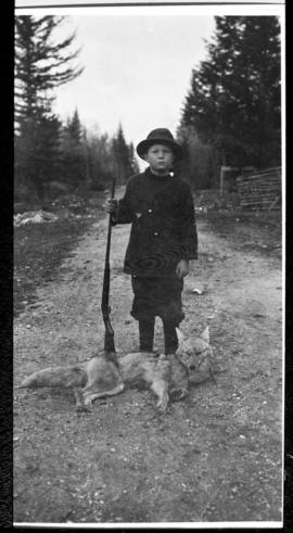 Portrait of a boy, rifle, and animal