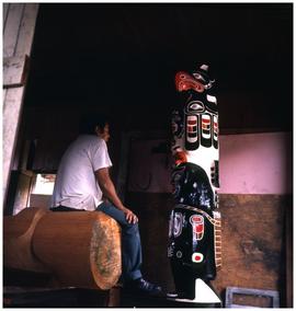 Sam Johnson, carver, with one of his totem poles, Gwayasdums