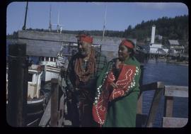 Man and woman in ceremonial dress on dock, Alert Bay