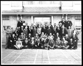 Group portrait of men in front of large building, view two
