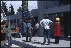 A totem pole being lifted by a crane