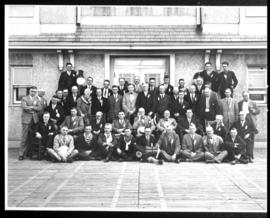 Group portrait of men in front of large building