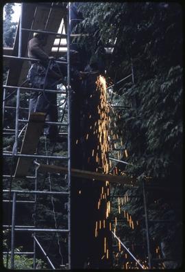Workers cutting a totem pole's support
