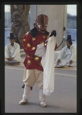 Masked dancer performs with a doll