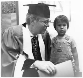 [Bill Reid in graduation gown with a child]
