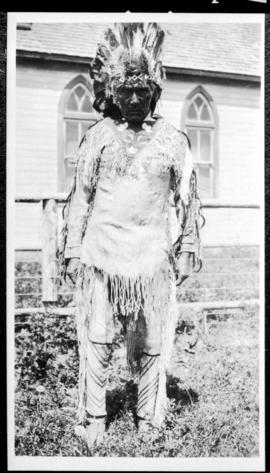 Portrait of a man in native dress  standing near a church