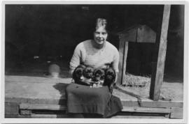Photo of a seated woman holding four puppies