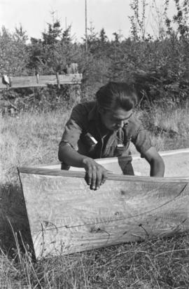 Man carving inside of canoe