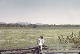 Chilcotin [woman on fence by field]