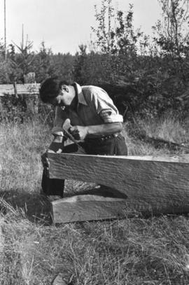 Man carving end of canoe